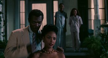 Movie still from “Eve's Bayou” (1997), directed by Kasi Lemmons – A man and a woman standing next to each other in front of other people; Medium shot, Over the shoulder angle