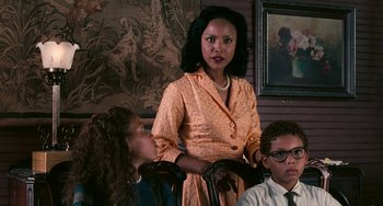 Movie still from “Eve's Bayou” (1997), directed by Kasi Lemmons – A woman in a yellow dress standing in front of two other people; Medium shot, Over the shoulder angle