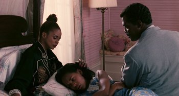 Movie still from “Eve's Bayou” (1997), directed by Kasi Lemmons – A young girl laying in a bed with her parents; Medium shot, High angle
