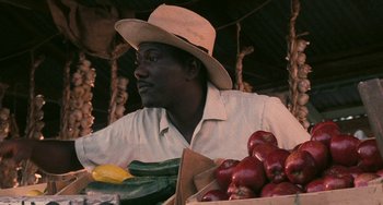 Movie still from “Eve's Bayou” (1997), directed by Kasi Lemmons – A man sitting at a table with a box of apples; Close Up shot, Over the shoulder angle