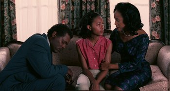 Movie still from “Eve's Bayou” (1997), directed by Kasi Lemmons – A man and two women sitting on a couch with a little girl; Medium shot, High angle