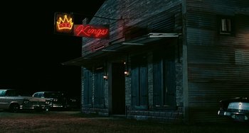 Movie still from “Eve's Bayou” (1997), directed by Kasi Lemmons – A neon sign is lit up on the side of a building; Extreme Wide shot, Low angle