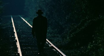 Movie still from “Eve's Bayou” (1997), directed by Kasi Lemmons – A man in a hat is walking on the train tracks at night; Wide shot, High angle