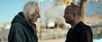 Movie still from “El Camino: A Breaking Bad Movie” (2019), directed by Vince Gilligan – Two men standing next to each other on the street; Close Up shot, Over the shoulder angle