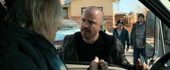 Movie still from “El Camino: A Breaking Bad Movie” (2019), directed by Vince Gilligan – A man in a leather jacket talking to a woman; Close Up shot, Over the shoulder angle