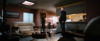 Movie still from “El Camino: A Breaking Bad Movie” (2019), directed by Vince Gilligan – A man standing in front of a mirror in a living room; Wide shot, Over the shoulder angle