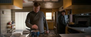 Movie still from “El Camino: A Breaking Bad Movie” (2019), directed by Vince Gilligan – A man standing in front of an open oven cooking food; Medium shot, Over the shoulder angle