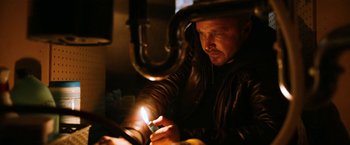 Movie still from “El Camino: A Breaking Bad Movie” (2019), directed by Vince Gilligan – A man lighting a candle in a dark room; Close Up shot, Low angle