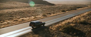 Movie still from “El Camino: A Breaking Bad Movie” (2019), directed by Vince Gilligan – A car driving down a road in the middle of the desert; Extreme Wide shot, High angle