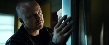 Movie still from “El Camino: A Breaking Bad Movie” (2019), directed by Vince Gilligan – A man looking at a window in a dark room; Close Up shot, Over the shoulder angle