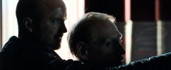 Movie still from “El Camino: A Breaking Bad Movie” (2019), directed by Vince Gilligan – Two men are looking at each other in the dark; Close Up shot, Over the shoulder angle
