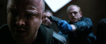 Movie still from “El Camino: A Breaking Bad Movie” (2019), directed by Vince Gilligan – A man with a gun in his hand and another man with a gun in his other hand; Close Up shot, Low angle