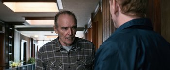 Movie still from “El Camino: A Breaking Bad Movie” (2019), directed by Vince Gilligan – An older man talking to a younger man in a hallway; Medium shot, Over the shoulder angle