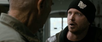 Movie still from “El Camino: A Breaking Bad Movie” (2019), directed by Vince Gilligan – A man in a black hat and a man in a brown jacket; Close Up shot, Over the shoulder angle