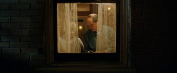 Movie still from “El Camino: A Breaking Bad Movie” (2019), directed by Vince Gilligan – An older man and a younger woman looking out of a window; Medium shot, Over the shoulder angle