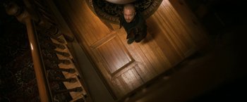 Movie still from “El Camino: A Breaking Bad Movie” (2019), directed by Vince Gilligan – A man standing on a wooden floor looking up at the ceiling; Wide shot, Overhead angle