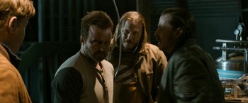 Movie still from “El Camino: A Breaking Bad Movie” (2019), directed by Vince Gilligan – A group of men standing next to each other on a street; Medium shot, Over the shoulder angle