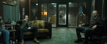Movie still from “El Camino: A Breaking Bad Movie” (2019), directed by Vince Gilligan – A person sitting on a couch in a room; Wide shot, Low angle