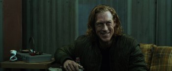 Movie still from “El Camino: A Breaking Bad Movie” (2019), directed by Vince Gilligan – A person with long hair smiling; Close Up shot, Over the shoulder angle