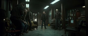 Movie still from “El Camino: A Breaking Bad Movie” (2019), directed by Vince Gilligan – A group of people standing in a room; Wide shot, High angle