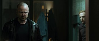 Movie still from “El Camino: A Breaking Bad Movie” (2019), directed by Vince Gilligan – A person wearing a leather jacket in a dark room; Close Up shot, Over the shoulder angle