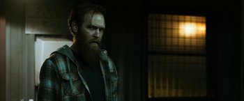 Movie still from “El Camino: A Breaking Bad Movie” (2019), directed by Vince Gilligan – A man with a beard and a plaid jacket; Medium shot, Over the shoulder angle