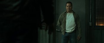 Movie still from “El Camino: A Breaking Bad Movie” (2019), directed by Vince Gilligan – A man standing in front of a door with his hands in his pockets; Medium shot, Over the shoulder angle