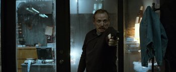 Movie still from “El Camino: A Breaking Bad Movie” (2019), directed by Vince Gilligan – A man holding a gun in a room; Medium shot, Low angle