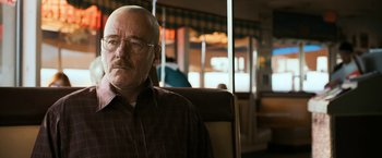 Movie still from “El Camino: A Breaking Bad Movie” (2019), directed by Vince Gilligan – An older man sitting in a chair in front of a window; Close Up shot, Over the shoulder angle