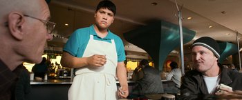 Movie still from “El Camino: A Breaking Bad Movie” (2019), directed by Vince Gilligan – A man wearing an apron and holding a knife; Medium shot, Low angle