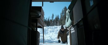Movie still from “El Camino: A Breaking Bad Movie” (2019), directed by Vince Gilligan – A man in a brown jacket and a brown hat is in the snow; Wide shot, High angle