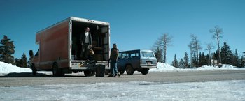 Movie still from “El Camino: A Breaking Bad Movie” (2019), directed by Vince Gilligan – Two men unloading a truck from the back of a van; Wide shot, Low angle