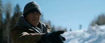 Movie still from “El Camino: A Breaking Bad Movie” (2019), directed by Vince Gilligan – An older man wearing a hat and gloves in the snow; Medium shot, Over the shoulder angle