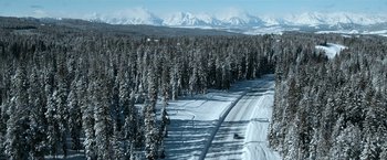 Movie still from “El Camino: A Breaking Bad Movie” (2019), directed by Vince Gilligan – An aerial view of a snowy forest and a road; Extreme Wide shot, High angle