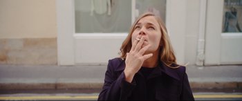 Movie still from “Everybody Loves Jeanne” (2022), directed by Céline Devaux – A woman is smoking a cigarette on the street; Close Up shot, Low angle