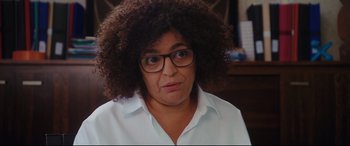 Movie still from “Everybody Loves Jeanne” (2022), directed by Céline Devaux – A woman with glasses is looking at the camera; Close Up shot, Over the shoulder angle