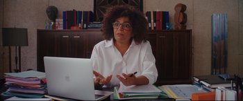 Movie still from “Everybody Loves Jeanne” (2022), directed by Céline Devaux – A woman sitting in front of a computer at a desk; Medium shot, Over the shoulder angle