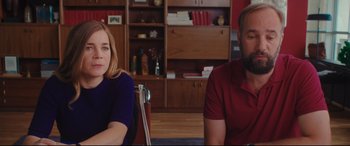 Movie still from “Everybody Loves Jeanne” (2022), directed by Céline Devaux – A woman and a man sitting next to each other in a room; Medium shot, Over the shoulder angle