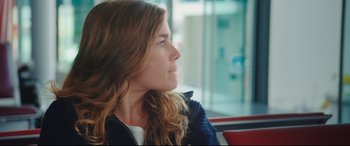 Movie still from “Everybody Loves Jeanne” (2022), directed by Céline Devaux – A person sitting in a chair; Close Up shot, Over the shoulder angle