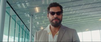 Movie still from “Everybody Loves Jeanne” (2022), directed by Céline Devaux – A man wearing a suit and sunglasses in a building; Close Up shot, Low angle