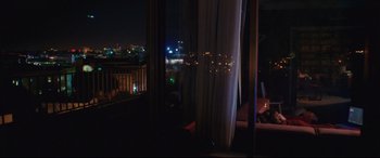 Movie still from “Everybody Loves Jeanne” (2022), directed by Céline Devaux – A view of a city at night through a window; Wide shot, Over the shoulder angle