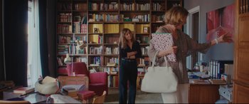 Movie still from “Everybody Loves Jeanne” (2022), directed by Céline Devaux – Two women standing in front of bookshelves in a library; Wide shot, Over the shoulder angle