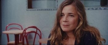Movie still from “Everybody Loves Jeanne” (2022), directed by Céline Devaux – A person sitting at a table; Close Up shot, Over the shoulder angle