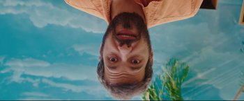 Movie still from “Everybody Loves Jeanne” (2022), directed by Céline Devaux – A man is upside down with his eyes wide open; Extreme Close Up shot, Overhead angle