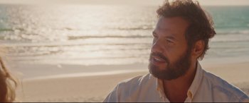 Movie still from “Everybody Loves Jeanne” (2022), directed by Céline Devaux – A person sitting on the beach; Close Up shot, Over the shoulder angle