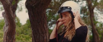 Movie still from “Everybody Loves Jeanne” (2022), directed by Céline Devaux – A woman wearing a white helmet and holding a leash; Close Up shot, Low angle