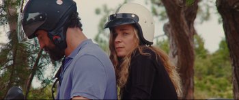 Movie still from “Everybody Loves Jeanne” (2022), directed by Céline Devaux – A young woman wearing a motorcycle helmet while standing next to a young man; Close Up shot, Over the shoulder angle