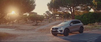 Movie still from “Everybody Loves Jeanne” (2022), directed by Céline Devaux – A car parked on the side of a road near a forest; Extreme Wide shot, Low angle