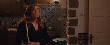 Movie still from “Everybody Loves Jeanne” (2022), directed by Céline Devaux – A woman standing in front of a wall in a room; Medium shot, High angle
