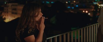 Movie still from “Everybody Loves Jeanne” (2022), directed by Céline Devaux – A woman is smoking a cigarette outside at night; Medium shot, High angle